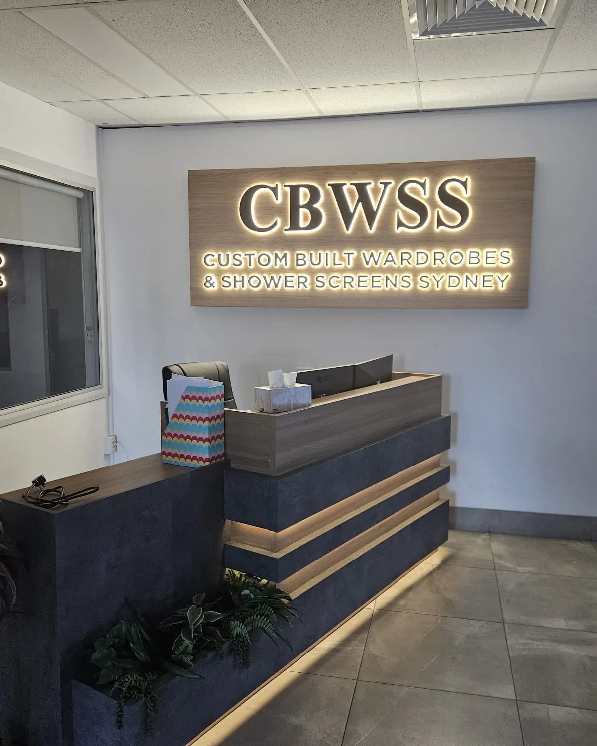 Backlit reception signage and downlights in a business reception area