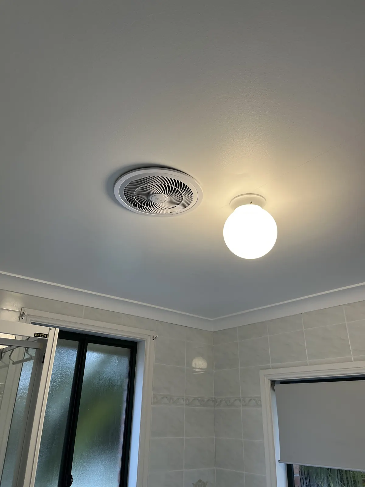 A round bathroom exhaust fan fitted by C3 Industries beside the ceiling light