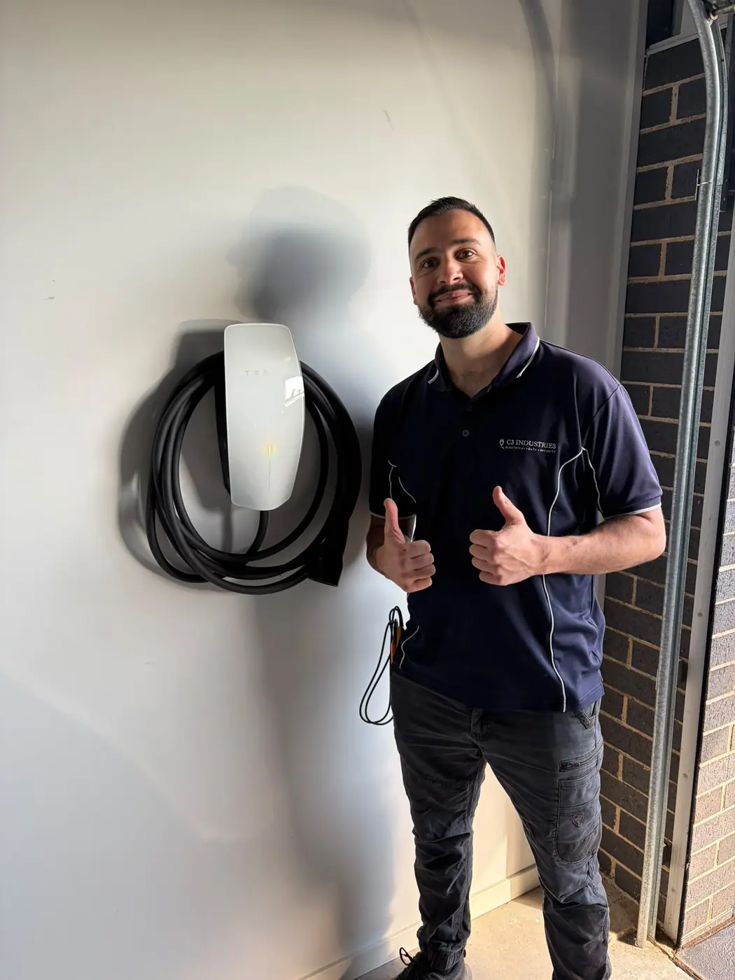 Kalin of C3 Industries beside a wall charger he has just installed in a garage