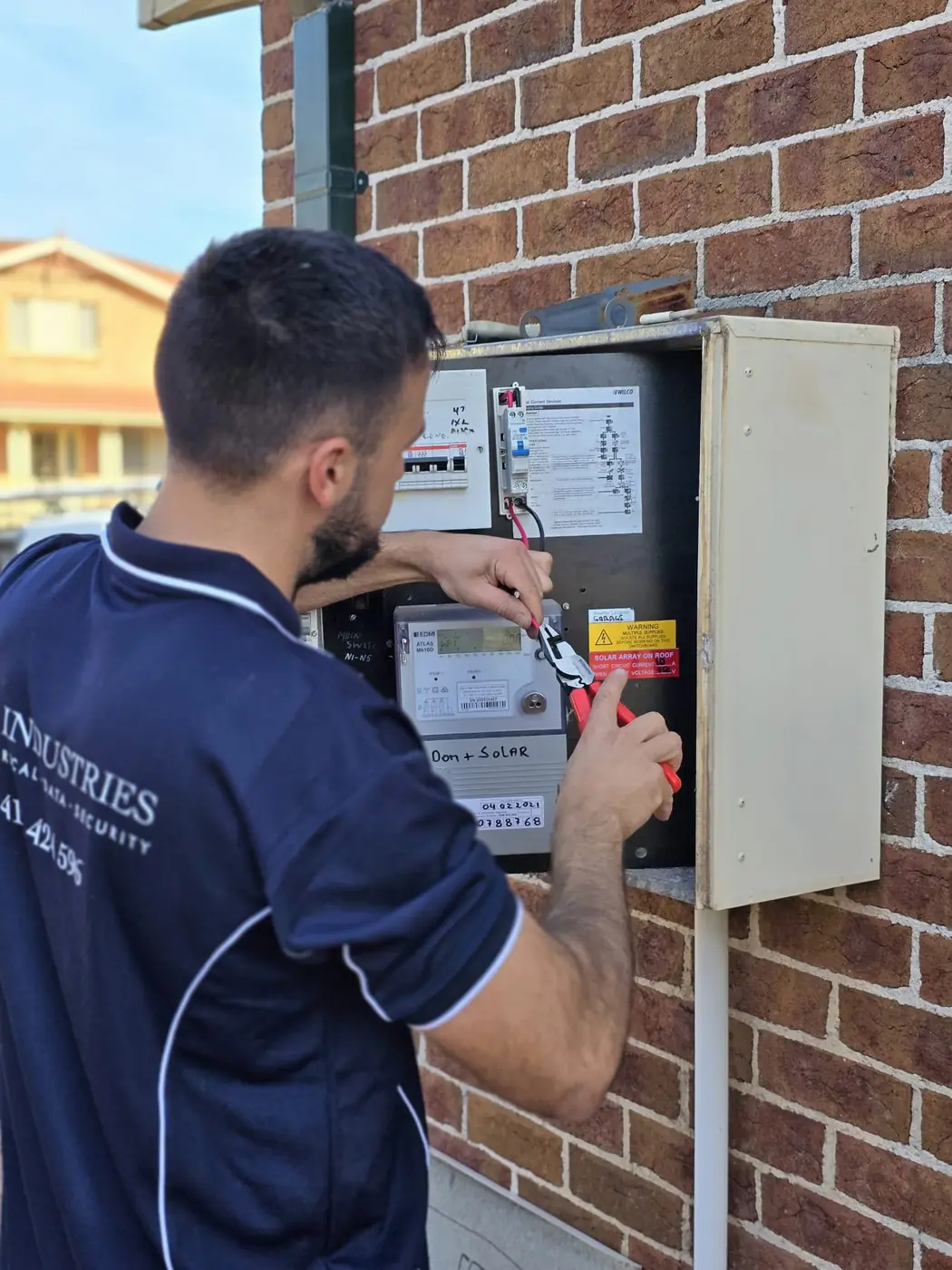 Kalin of C3 Industries testing a meter and switchboard on a brick wall