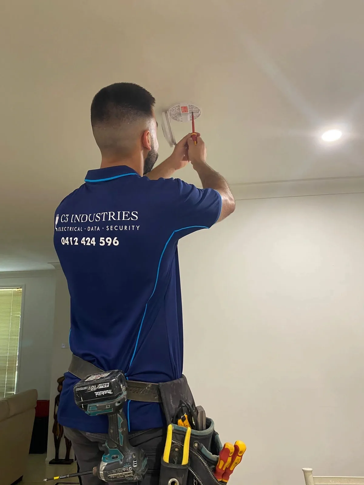 Kalin of C3 Industries fitting a smoke alarm to a ceiling