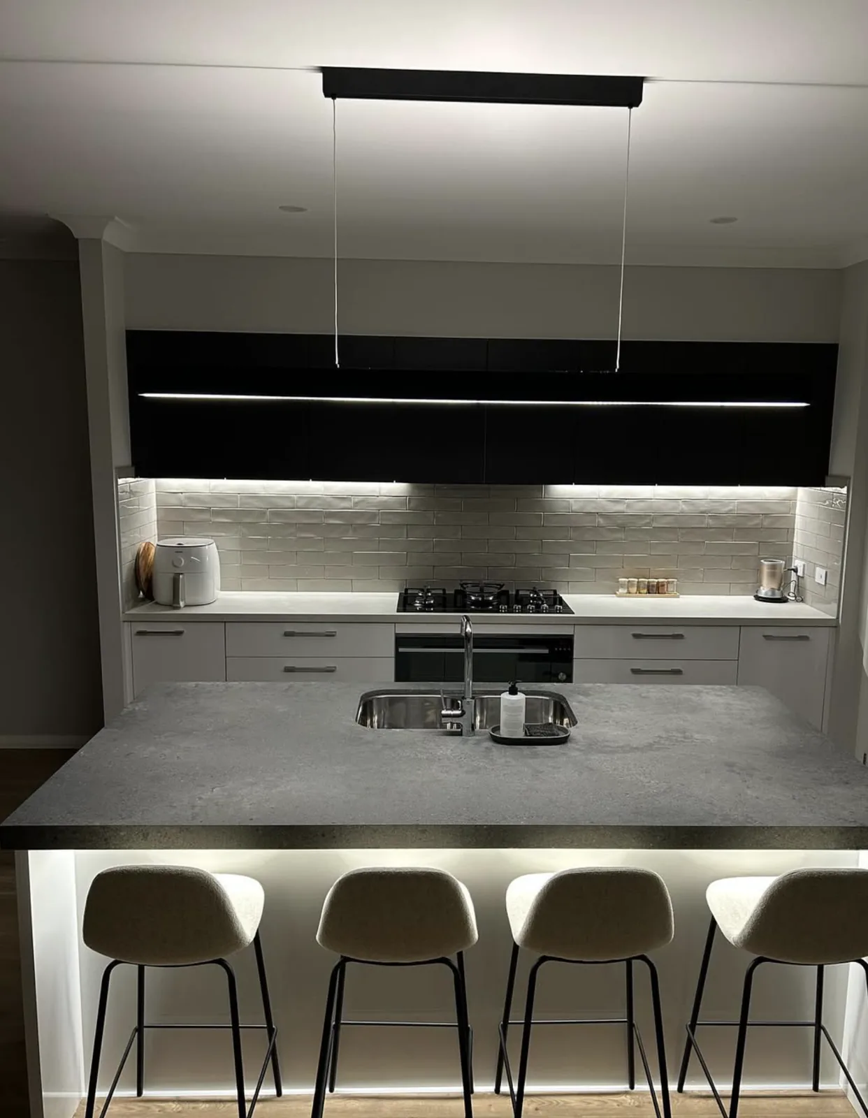 A kitchen island lit by pendant and strip lighting installed by C3 Industries