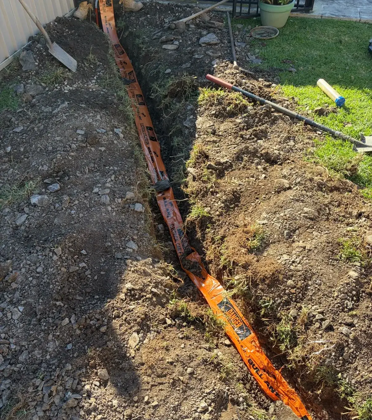 Orange electrical conduit laid in a trench during a new installation by C3 Industries